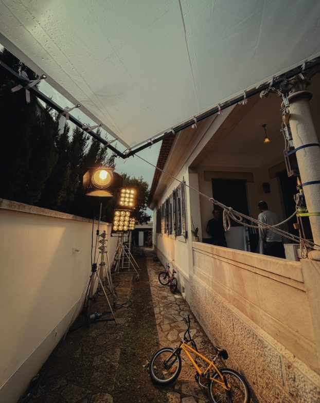 Exterior location with lighting setup, overhead cloth and film crew